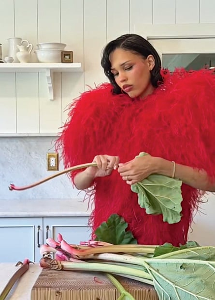Nara Smith looking serious while preparing rhubarb in her kitchen wearing an extravagant red fluffy outfit
