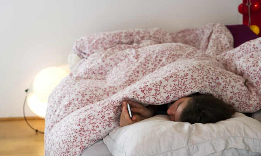 women under duvet covers reading smartphone