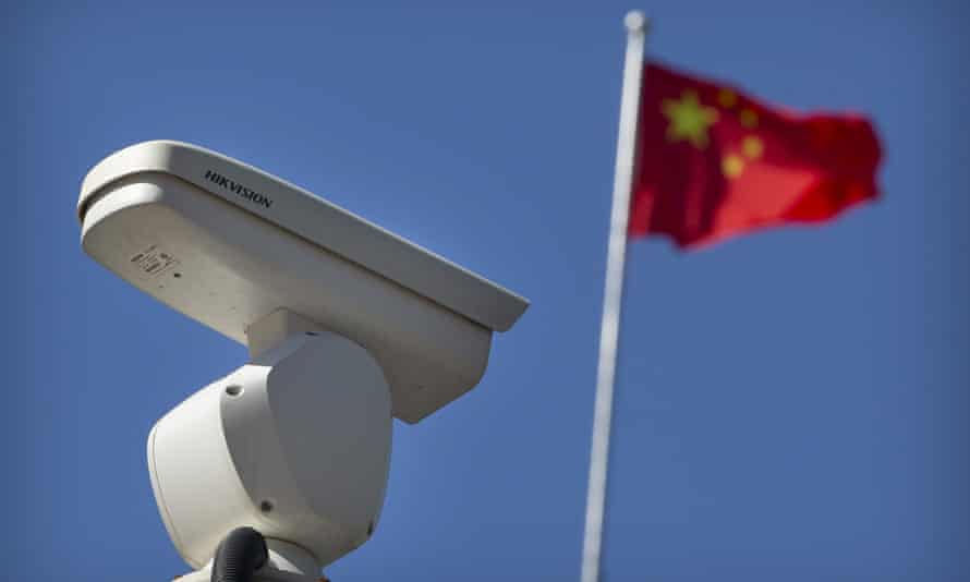 A Chinese flag flies near a security camera monitoring a traffic intersection in Beijing.