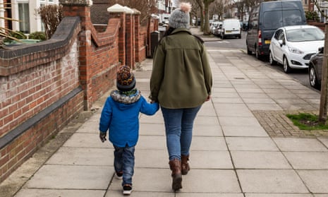 A mother and son walking on the pavement holding hands