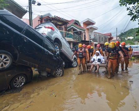 Rescuers carry a resident past cars washed away by floods at the height of Typhoon Kalmaegi at a subdivision of Cebu City in the central Philippines