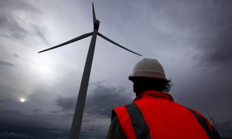 A worker walks between wind turbines at a windfarm.