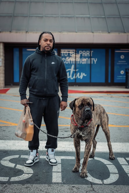 man holding grocery shopping bag stands outside store with his dog