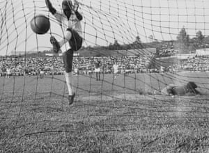 Pelé jumps into the net after scoring for Santos against Guarani of Paraguay in 1958