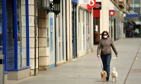 a woman walks her dog down an empty high street