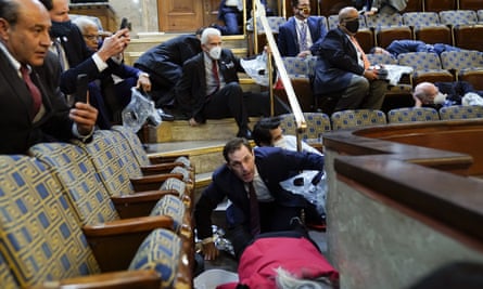 People shelter in the House gallery as protesters try to break into the chamber on 6 January.