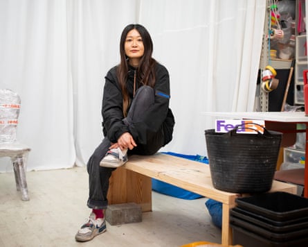 Kei Yoshino sits on a bench in her storeroom-like studio