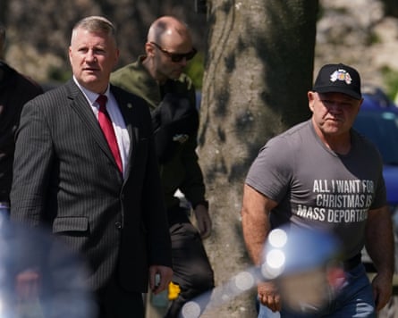 Paul Golding walking next to a man wearing a T-shirt saying ‘All I want for Christmas is mass deportations’