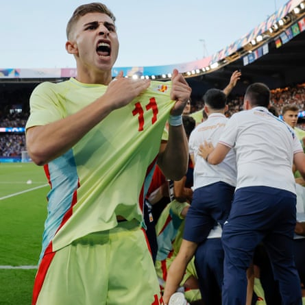 Fermin López of Spain points to the flag on his shirt as his team celebrate their fifth goal in the dying minutes of extra time of the gold medal football match against France.