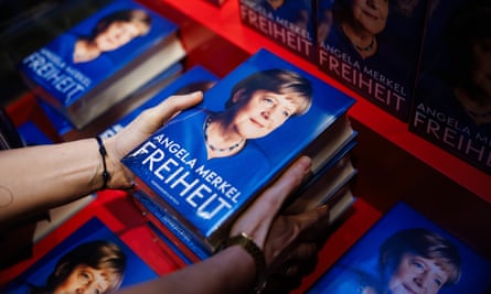 Hands hold book with Angela Merkel on the cover, with other copies below