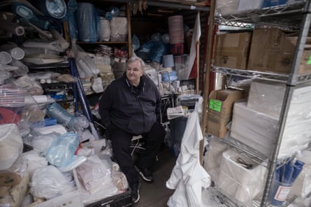 John Haykin sitting his shop; paper plates are stacked all around