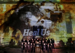 A school choir sings on the steps of Saint Luke's as visuals are projected on the walls.