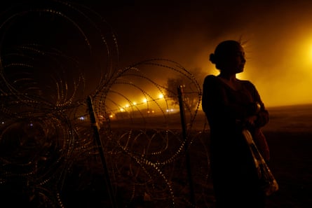 silhouette of woman in front of barbed wire against yellow light