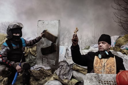 A priest faces a police officer with a shield while taking part in anti-government protests in Kyiv, Ukraine, February 20 2014