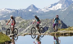 Three mountain bikers on a trail amid the Alps on the Les Arcs bike trail, France.