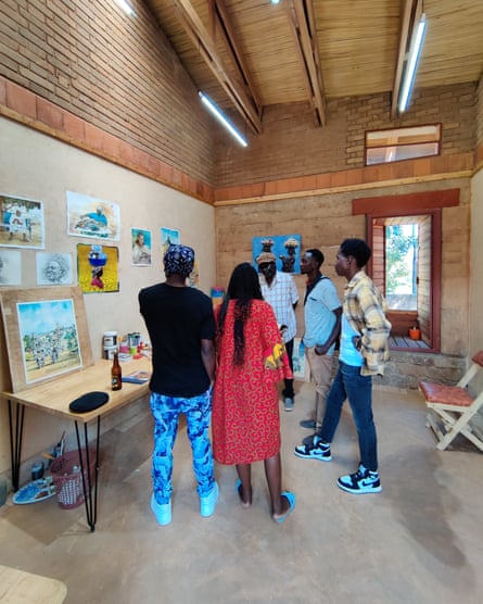 Four men and a woman stand in a semi-circle looking at pictures on a wall.