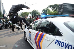 A person leaps to kick a police car