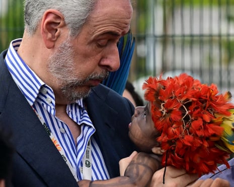 President Andre Correa do Lago holds a toddler during an indigenous protest at COP30