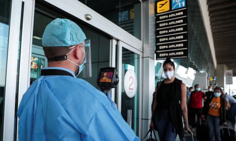 A healthcare worker measures the temperatures of travelers before entering the Tocumen International Airport during the coronavirus outbreak, in Panama City, Panama 16 October 2020.