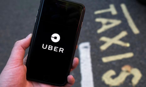 Uber app on phone, near 'taxis' sign on road