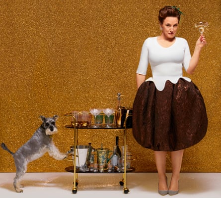 Grace Dent against gold background, with drinks trolley and glass in hand, and dog on other side of trolley