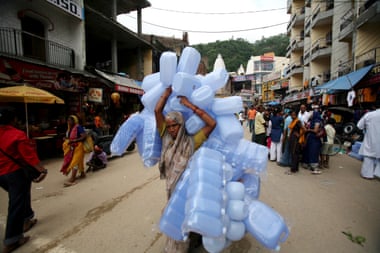 A woman carrying large number of plastic containers in Haridwar, Uttarakhand, India.
