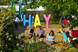 People relaxing on lawn in late afternoon summer sunshine in garden area at Hay Festival 2018 Hay-on-Wye Powys Wales