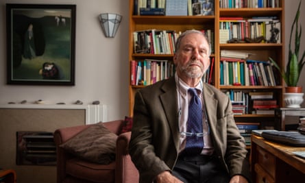 Dr David Bell poses for a photograph in his office, sitting at his desk in front of bookshelves