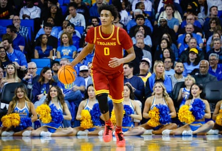 A young man dribbles a basketball as people watch.