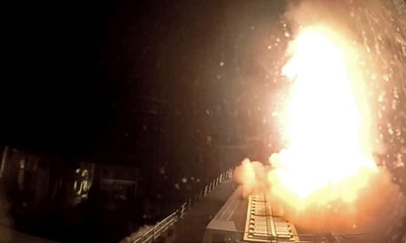 Flames of missile launch seen from deck of warship at night.