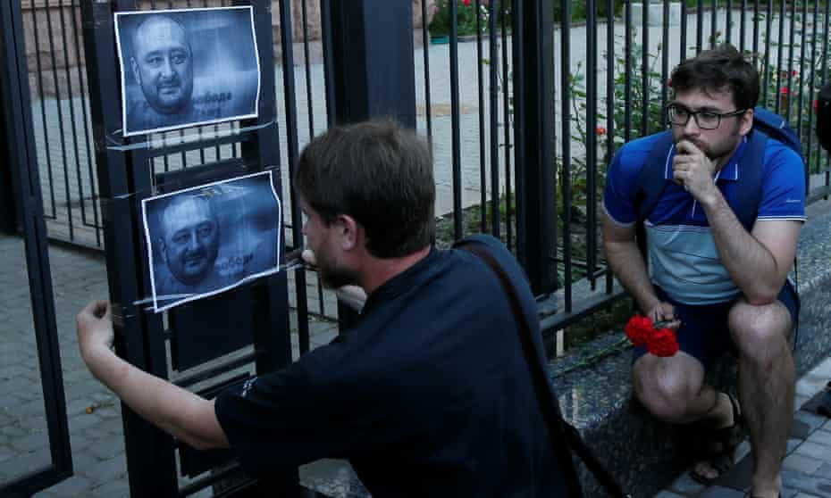A man hangs a picture of Arkady Babchenko on a fence outside the Russian embassy in Kiev, Ukraine.