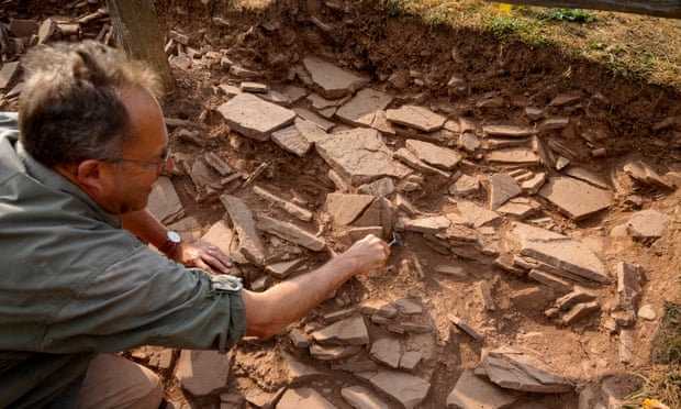 Thomas examines stones discovered, evidence of a wall around the site