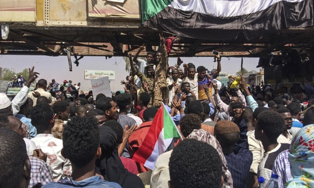 Sudanese soldiers flash the victory sign as they stand among protesters at a demonstration near the military headquarters in Khartoum