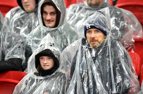 Fans in rain covers wait for the start of the match