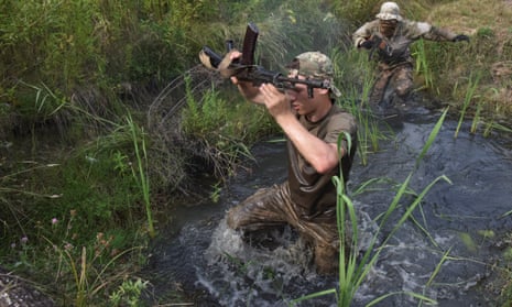 People cross an obstacle during military training in the Lviv region