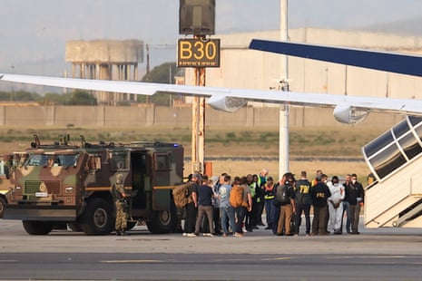 Men in FBI jackets shepherd a group of men on to a plane
