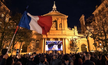 A French flag is waved as people gather on the Place de la Sorbonne in Paris to watch a live broadcast on a giant screen of a national homage at the Sorbonne University to French teacher Samuel Paty.
