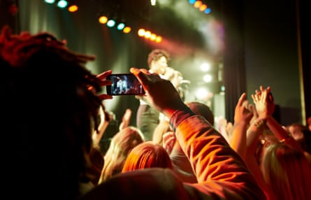 Someone holding a phone up to film a concert