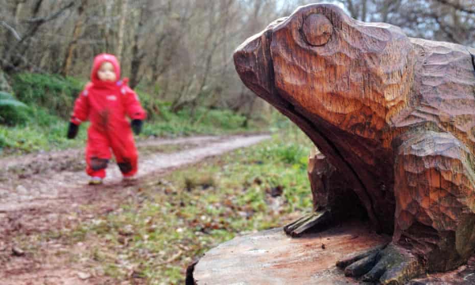 A toad sculpture attracts a toddler's interest on a trail in Pressmennan Woods, East Lothian.