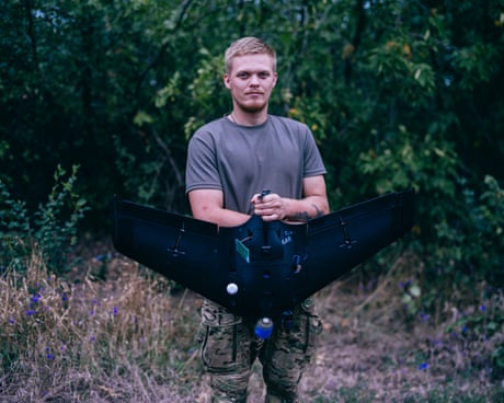 Buhan in T-shirt and combat trousers shows off a drone to camera