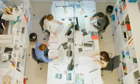 Overhead view of four persons working at desk in architects office
