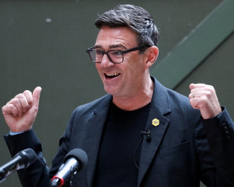 Andy Burnham smiling as he gives a press conference, fists raised