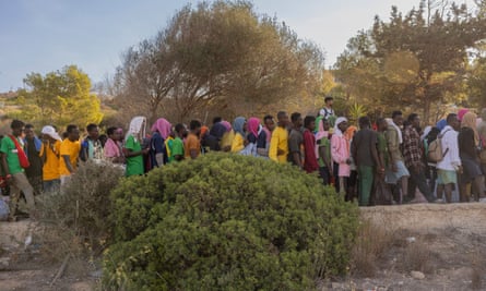 People wait on the road that leads to Lampedusa’s reception centre for migrants.