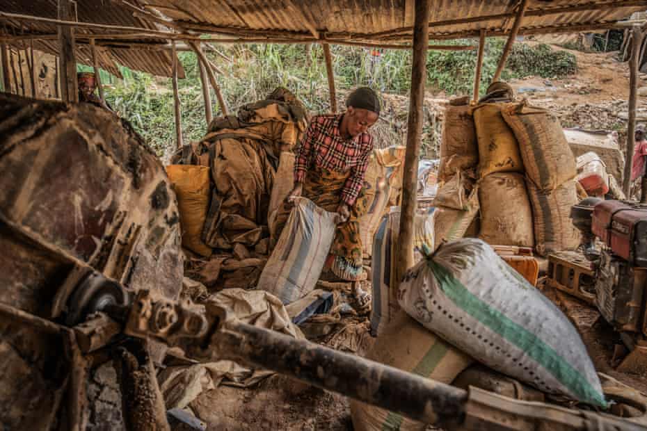 A woman loads sacks of sand to be filtered for gold particles at a mine in Kamituga.