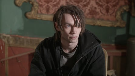 The musician Stefan Hoyle – AKA Syd Far-i – sitting down with the red and green walls behind him
