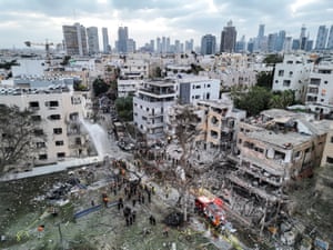 An aerial shot of firefighters dousing badly damaged apartment buildings with city centre skyscrapers in the background