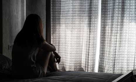 Rear view of depressed woman sitting on bed at home.