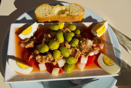 Plate with tuna, olives, eggs and tomatoes, and slice of crusty bread