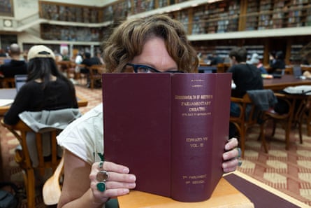 Crabb hides most of her face behind a large leather-bound book in the State Library