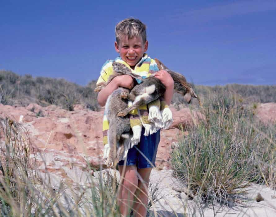 David McComb en tant que jeune enfant tenant des lapins sur une dune de sable.